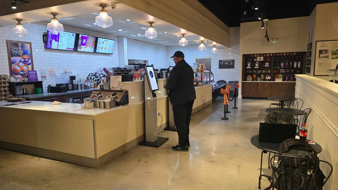 A customer ordering at an INFI kiosk in a coffee shop